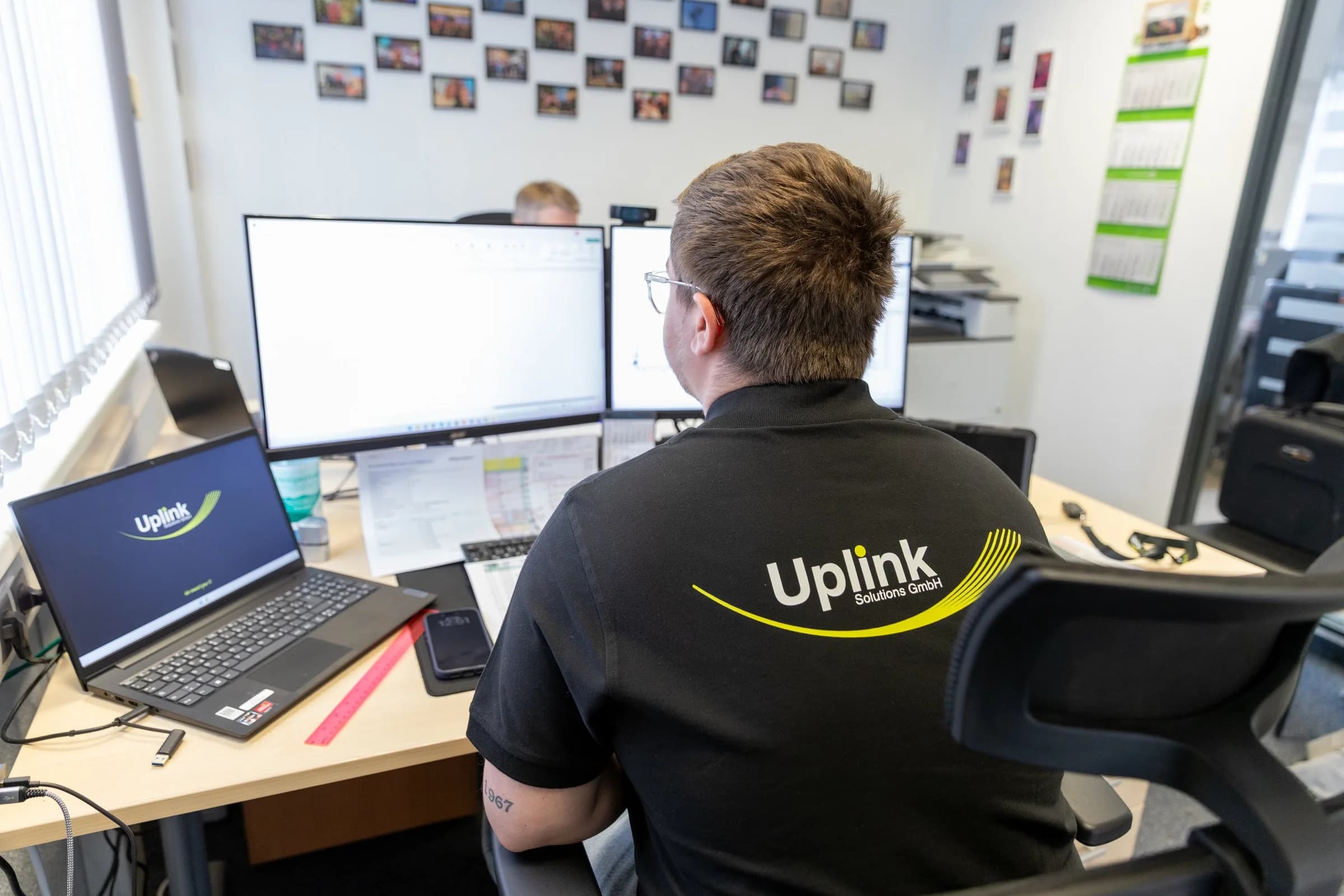 Mitarbeiter im Uplink-Poloshirt am Arbeitsplatz im Backoffice