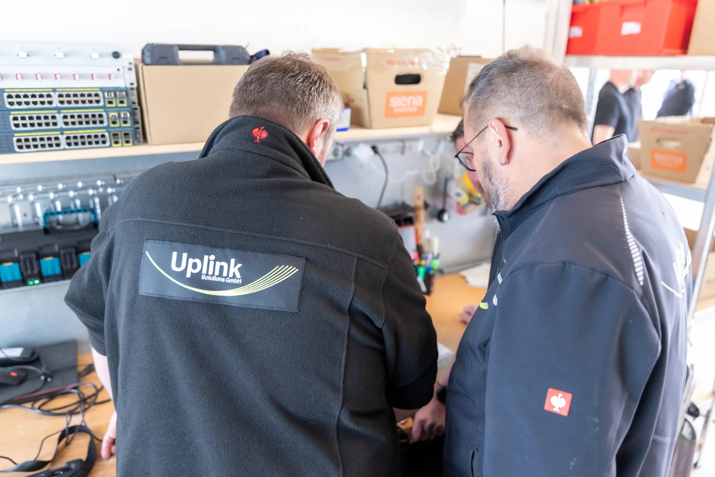Zwei Techniker arbeiten an Netzwerkhardware auf einer Werkbank