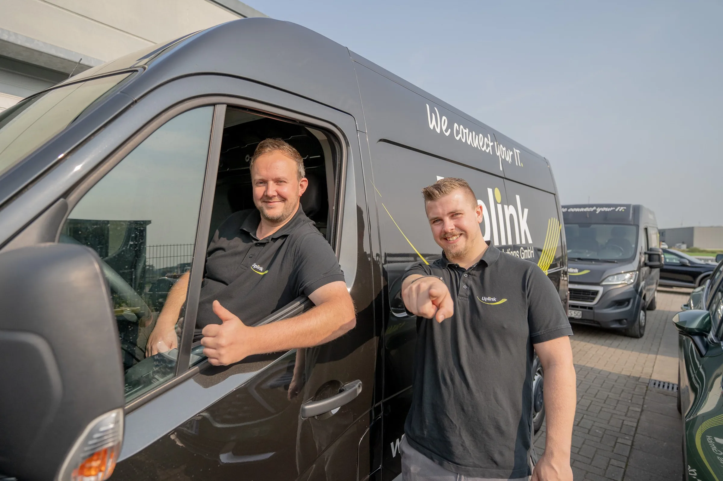 Zwei gut gelaunte Uplink-Techniker am Firmentransporter