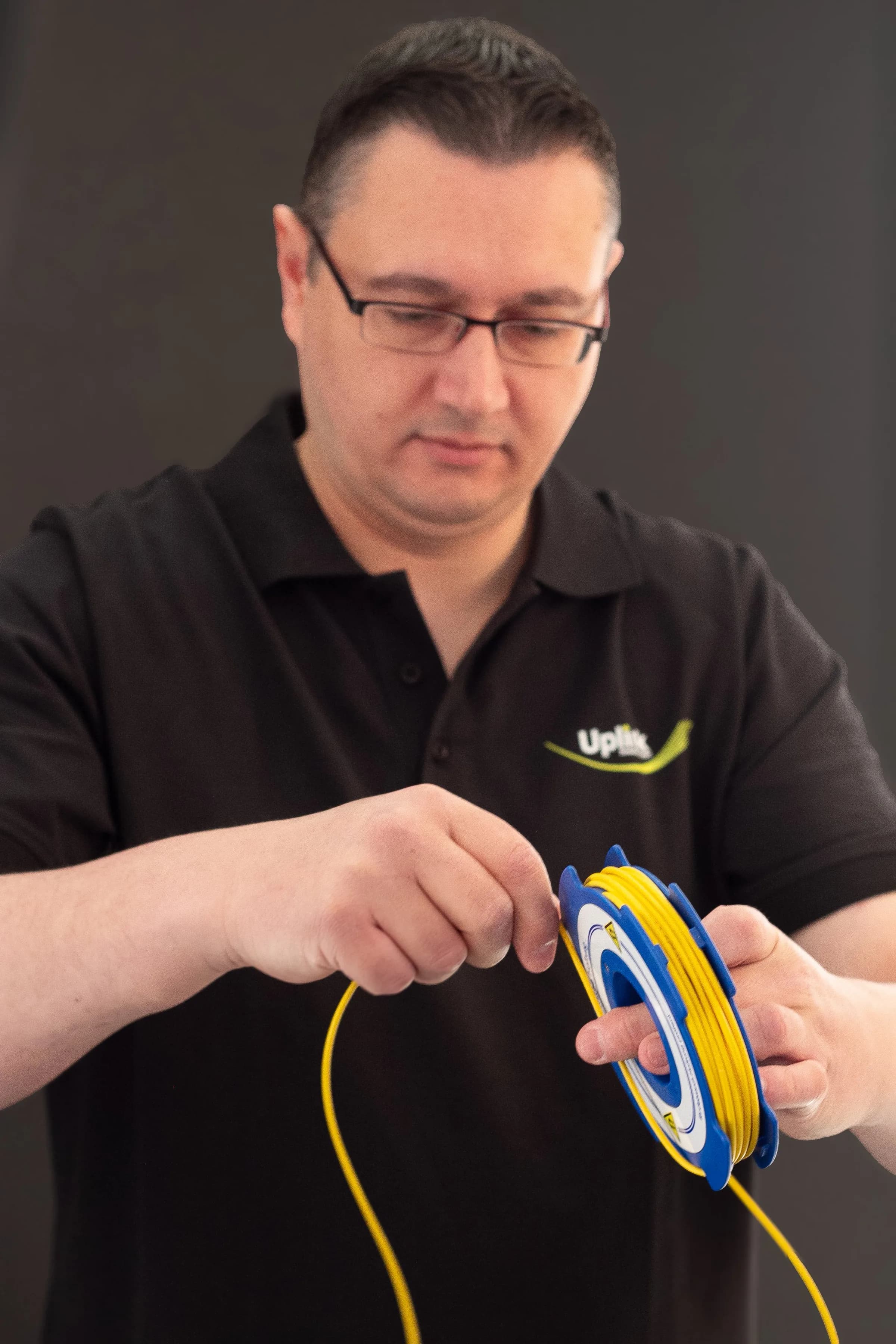 Techniker wickelt ein gelbes Glasfaserkabel von einer Spule ab