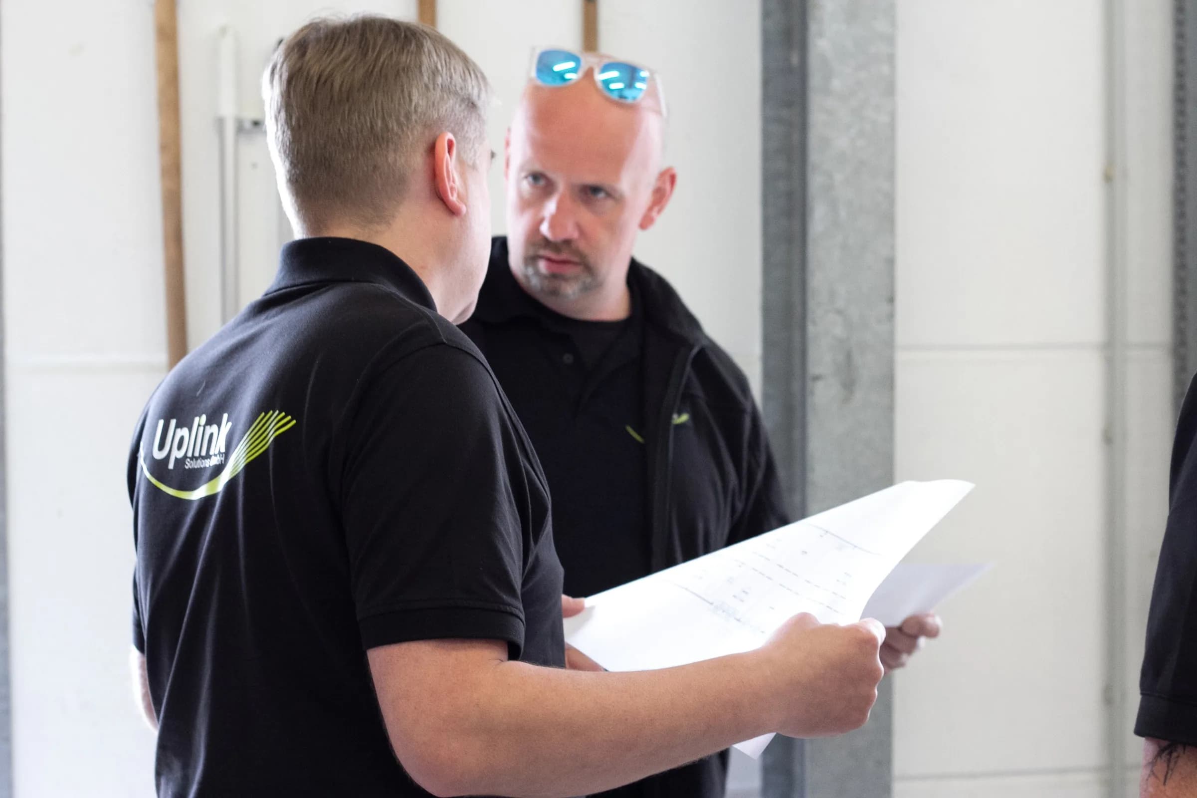 Zwei Uplink-Mitarbeiter besprechen ein Dokument in einem hellen Industrieraum