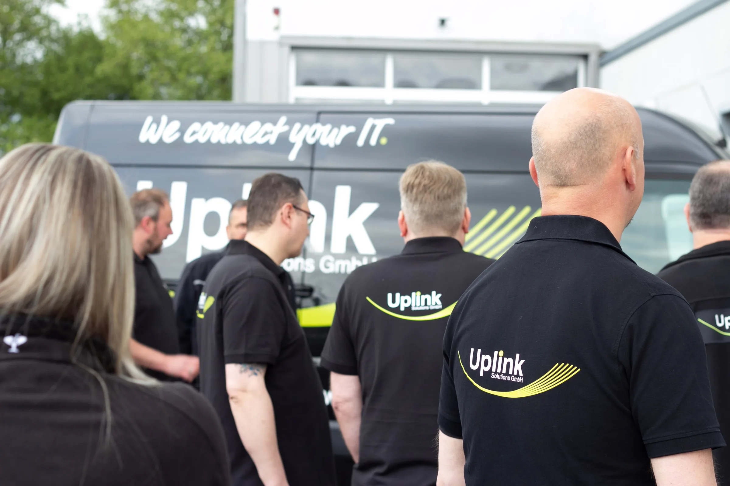 Uplink-Team vor einem Firmenwagen mit der Aufschrift „We connect your IT“