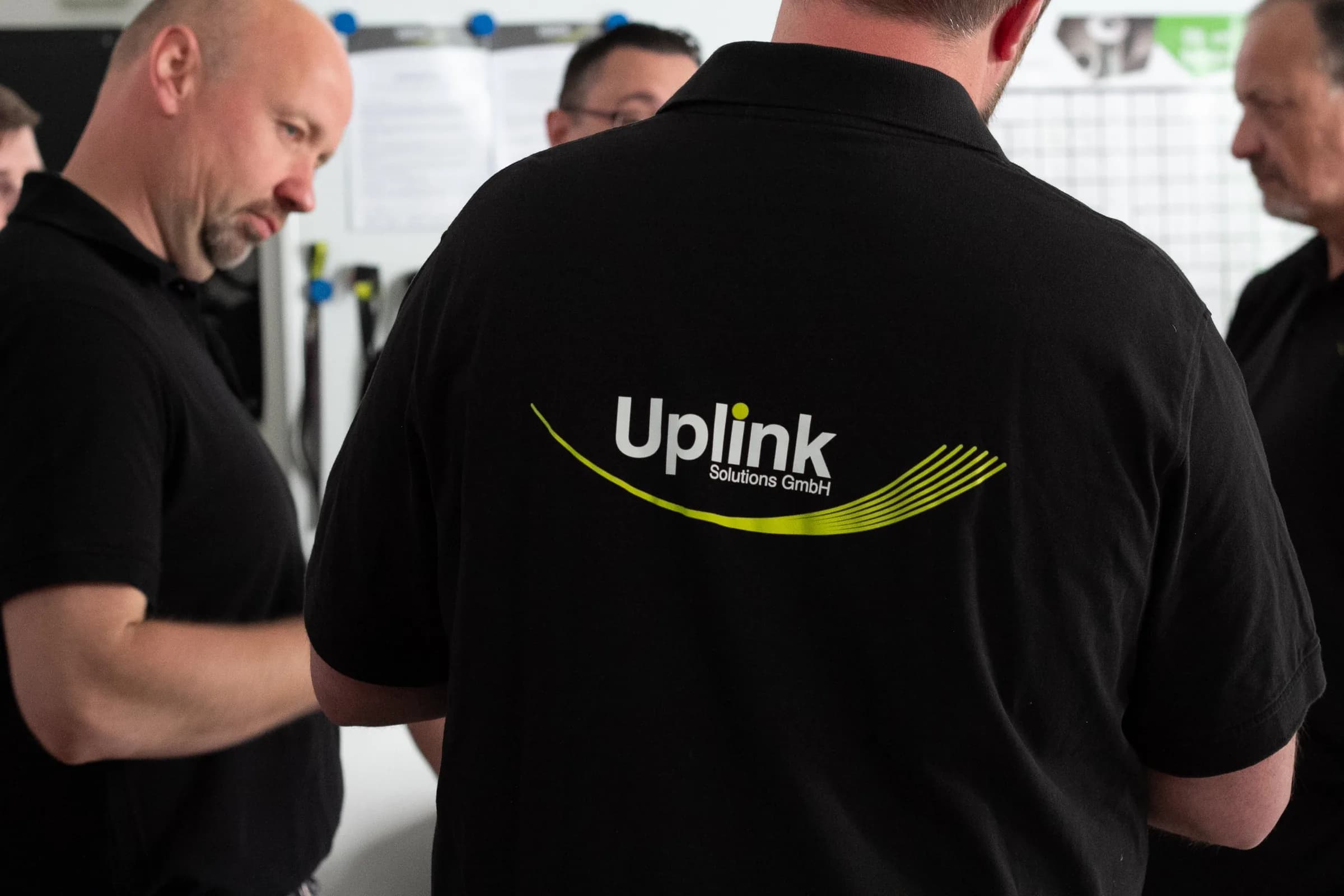 Uplink-Techniker in schwarzen Poloshirts stehen in einer Gruppe zusammen