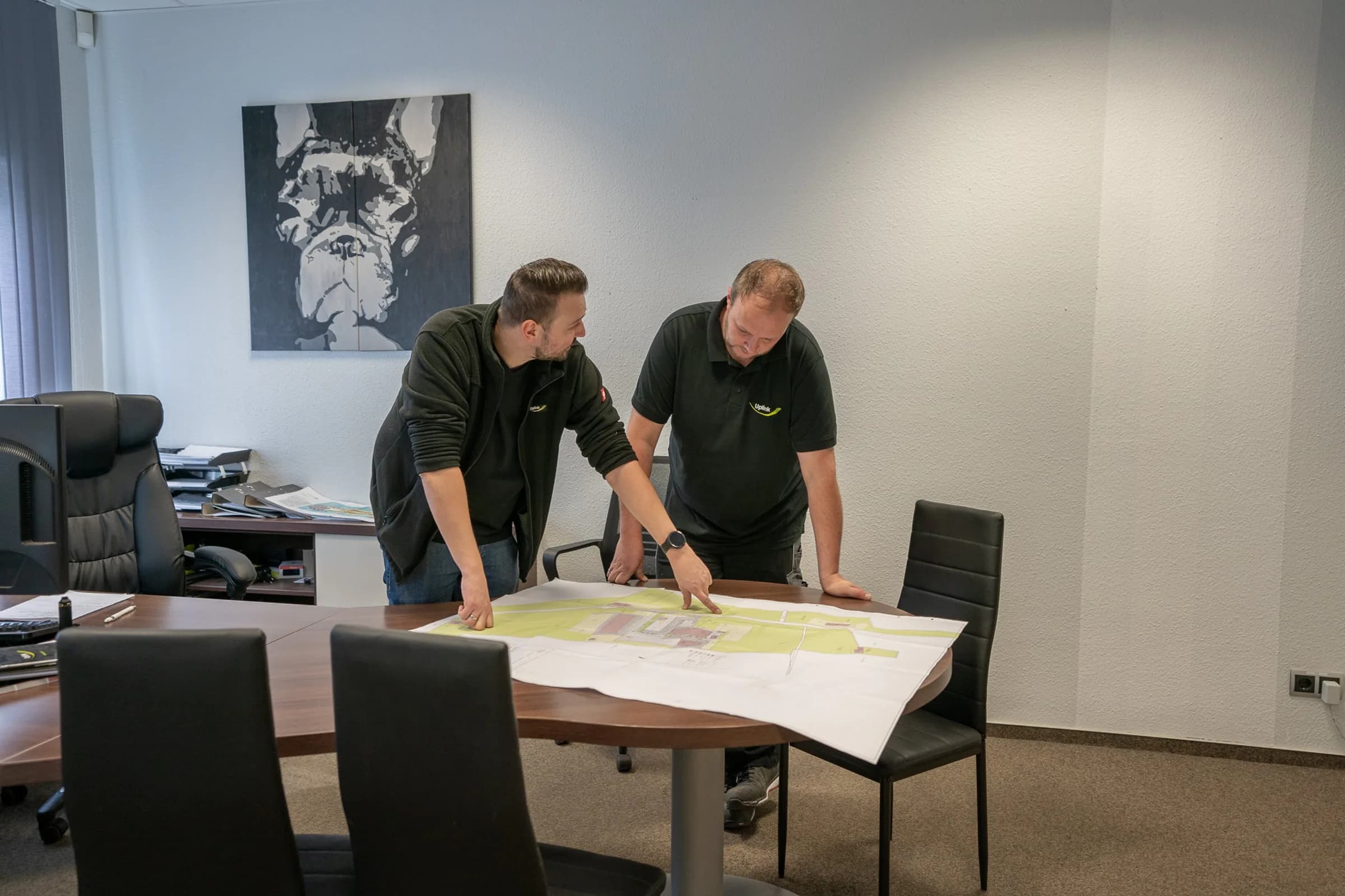 Zwei Uplink-Mitarbeiter besprechen einen ausgebreiteten Bauplan